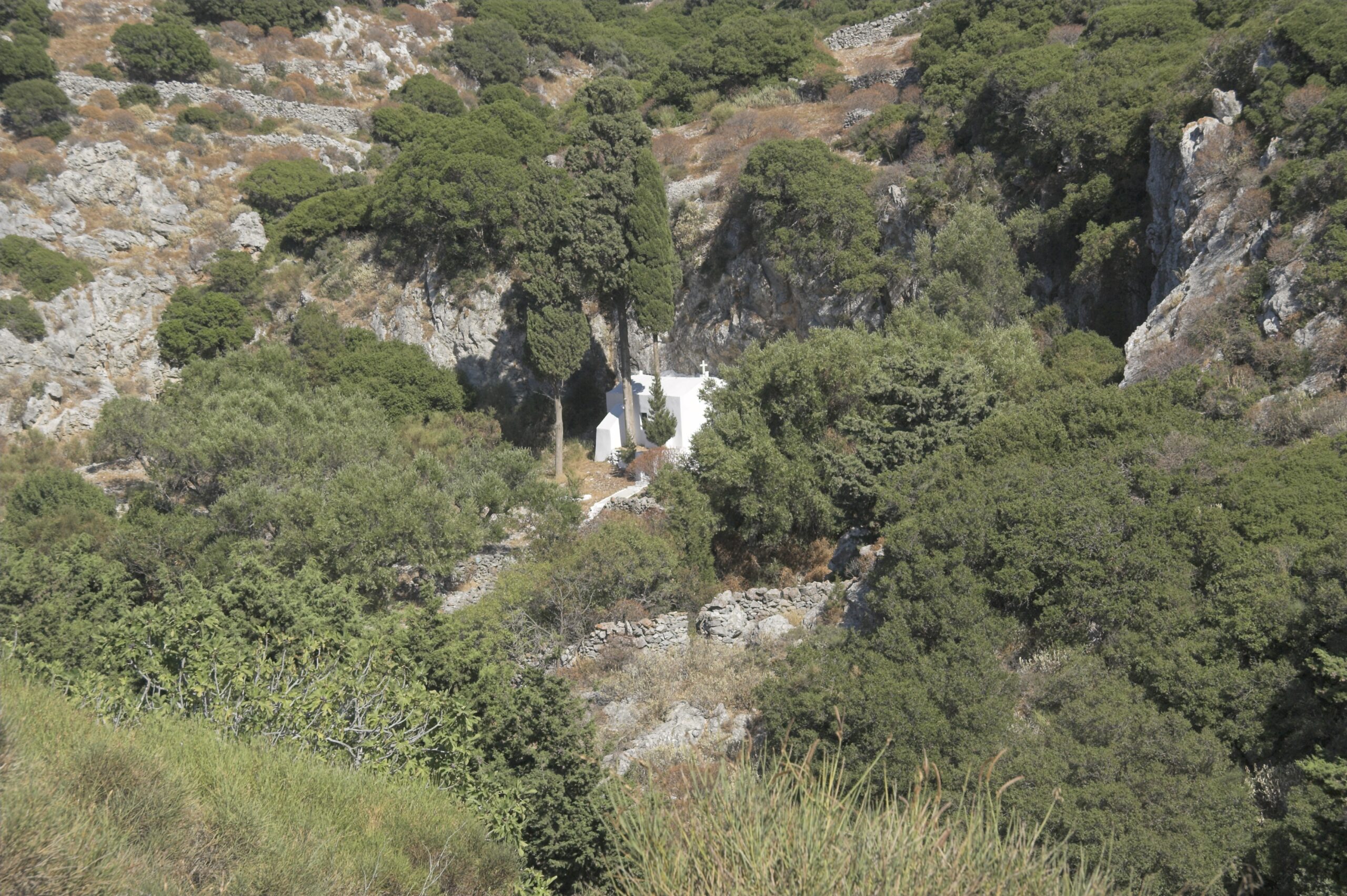 Whitewashed Cycladic chapel perched by the rocky coastline of Amorgos