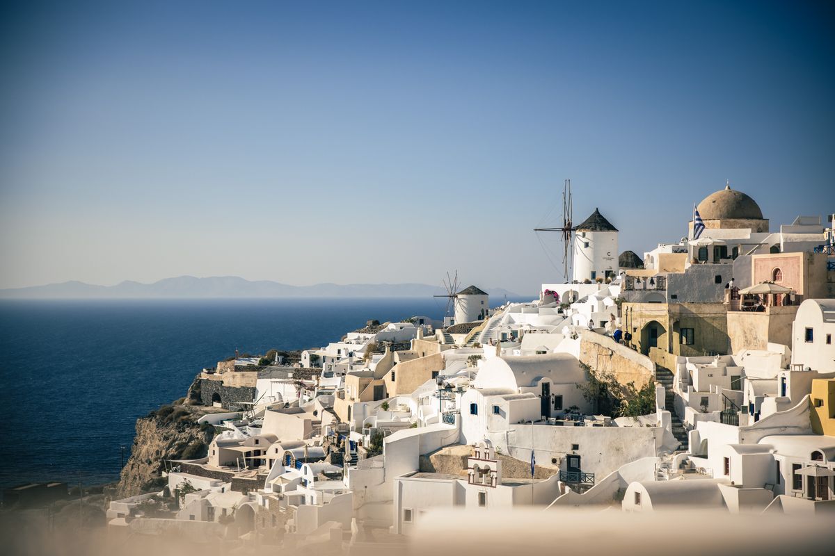 Whitewashed Cycladic houses bathed in warm golden sunset light on a Greek island