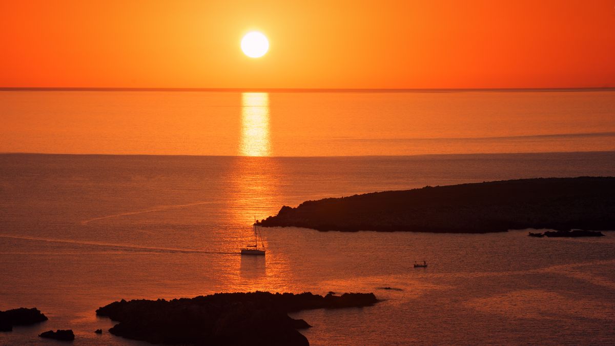 Golden hour calm Mediterranean sea with glowing orange and blue hues