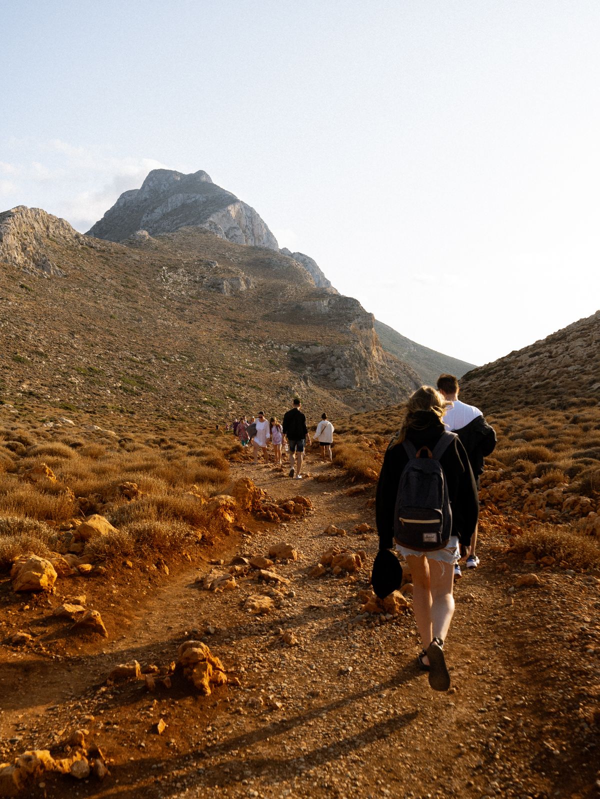 Mountain hiking trail winding through a green valley with clear blue sky