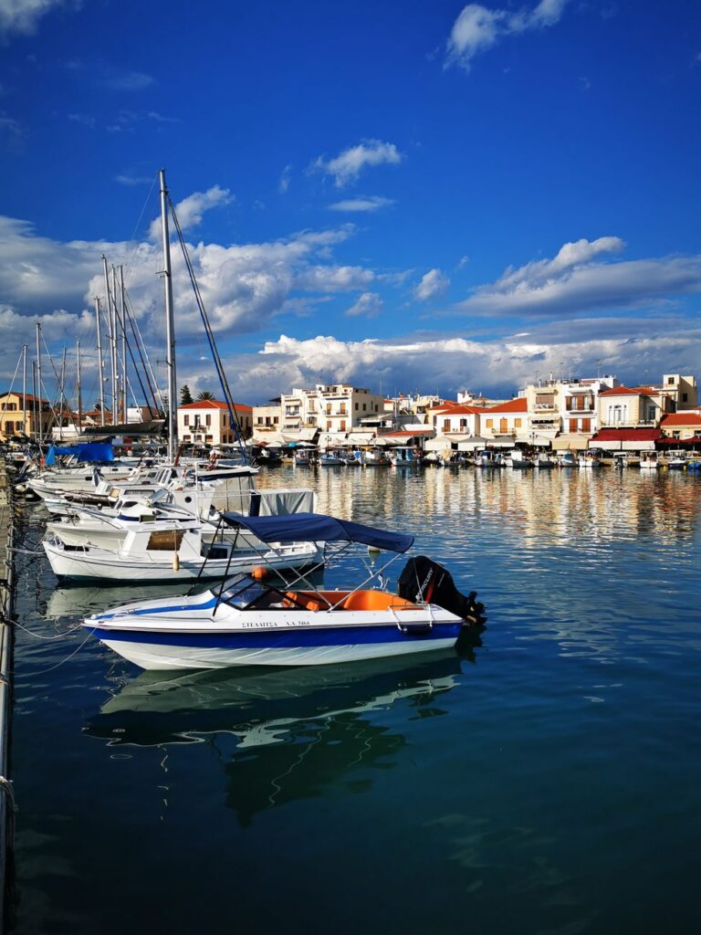Fishing boats docked at Aegina harbor with bright blue sky, Greece