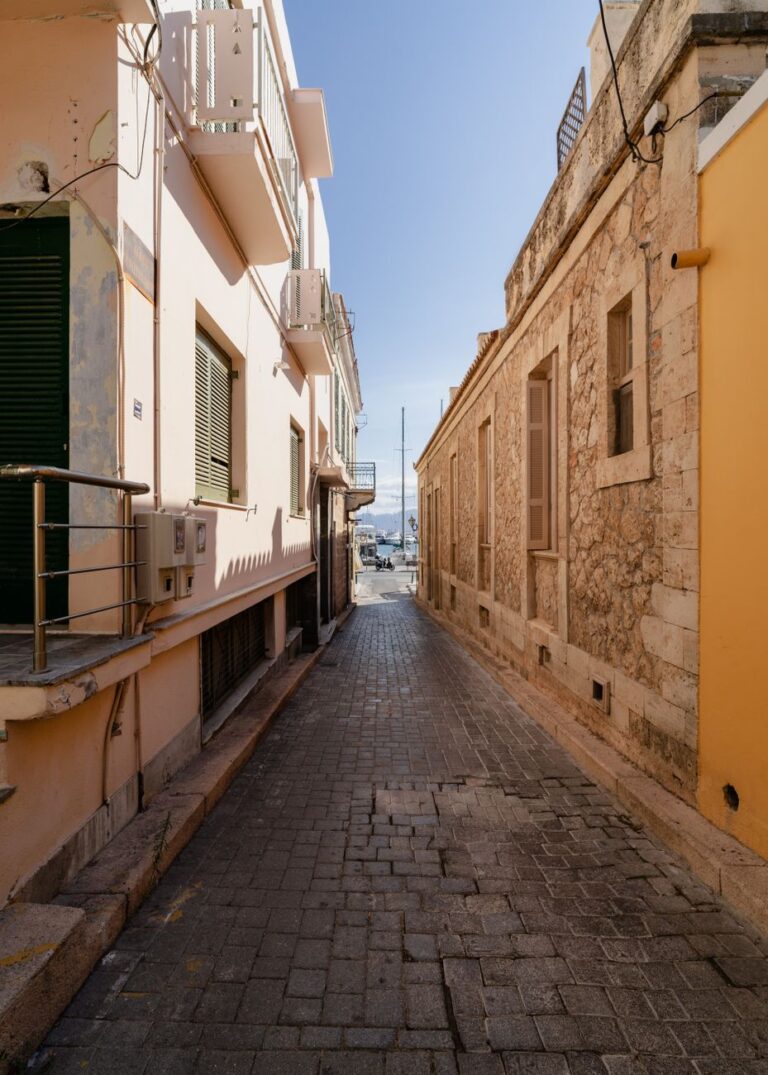 Traditional cobblestone alley in Aegina Town with pastel buildings, Greece
