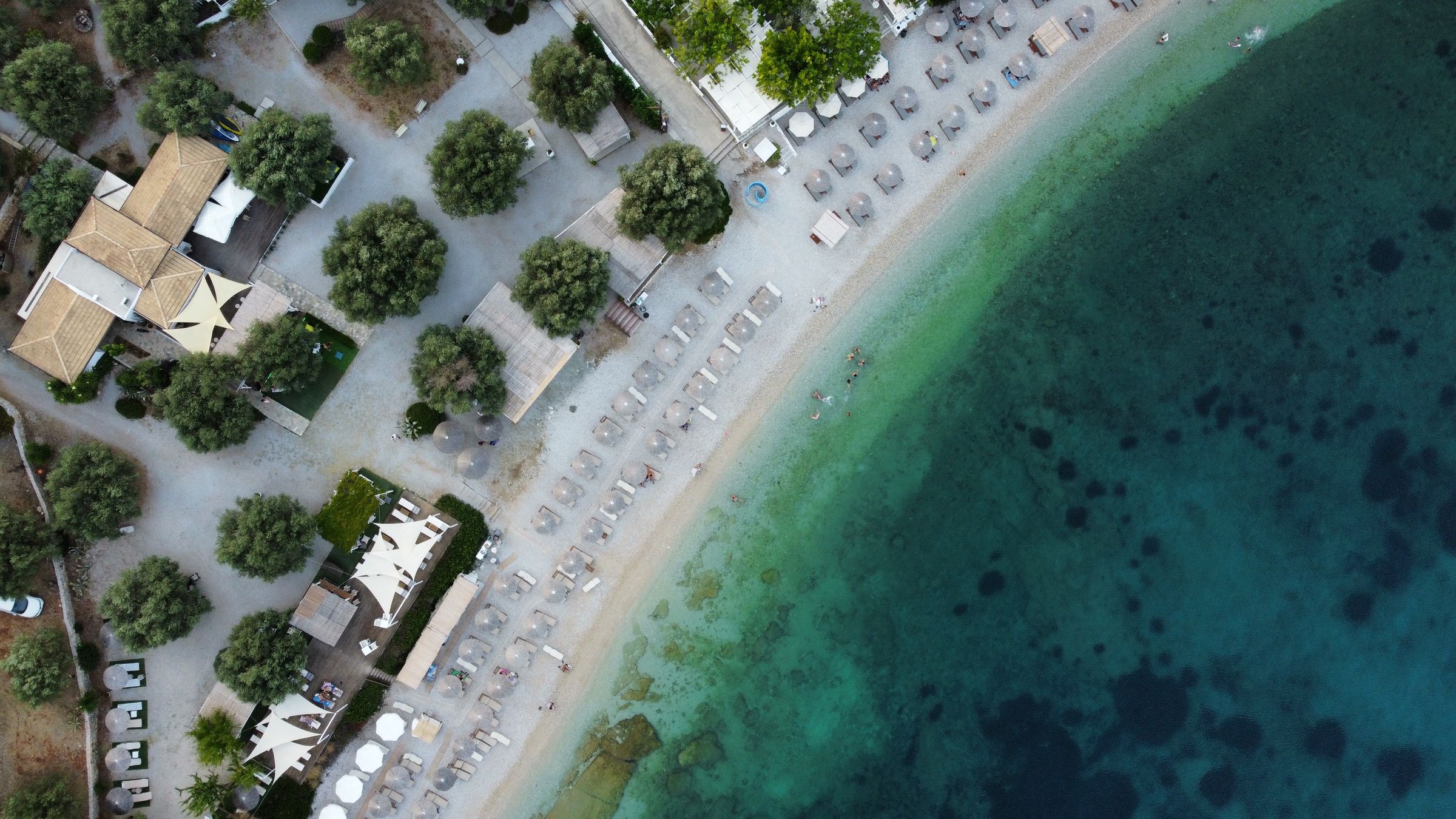 Aerial view of an organised beach with sun umbrellas and pine trees on Alonissos