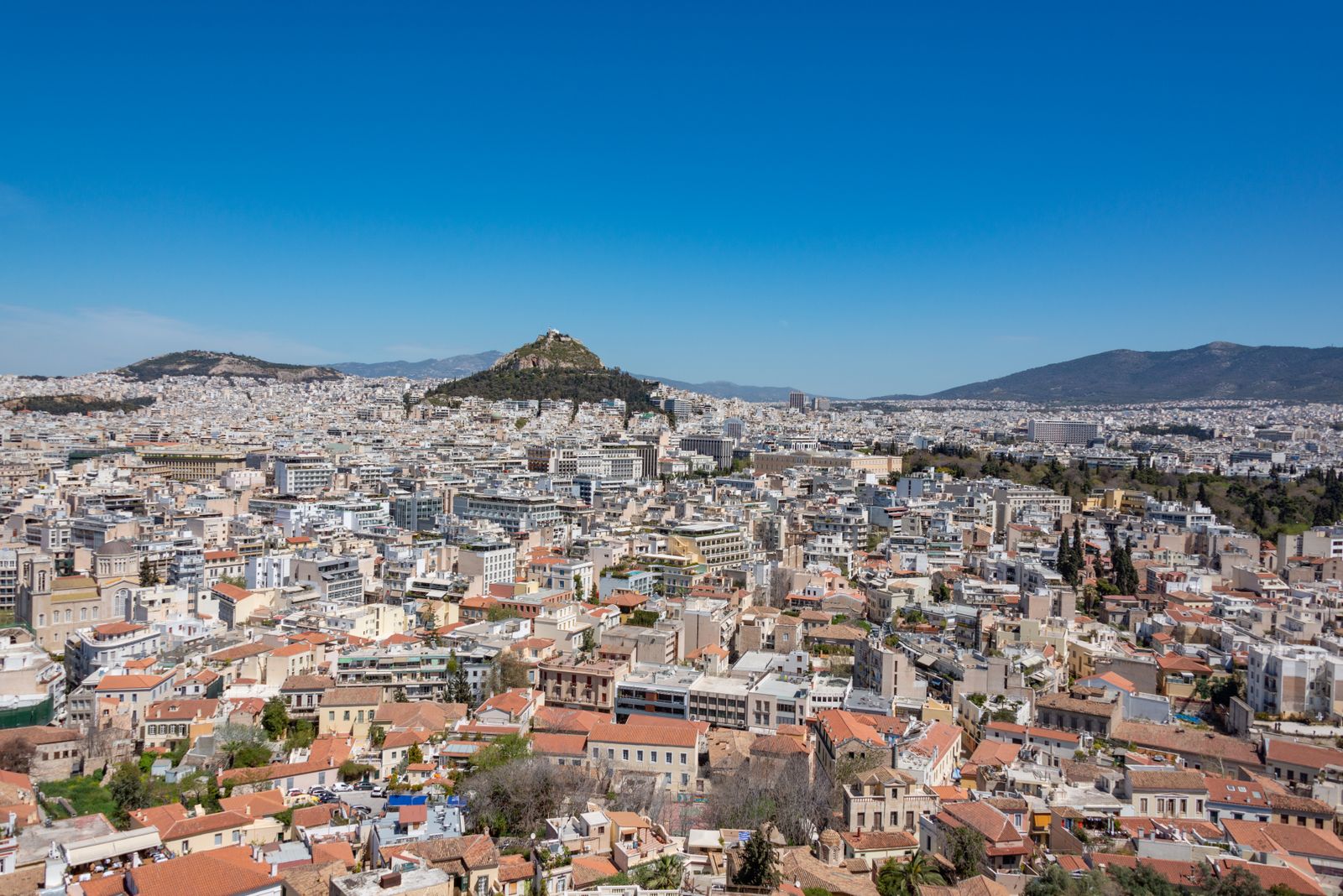 Panoramic view of Athens from above with Lycabettus Hill rising above the urban cityscape and the Acropolis in the distance