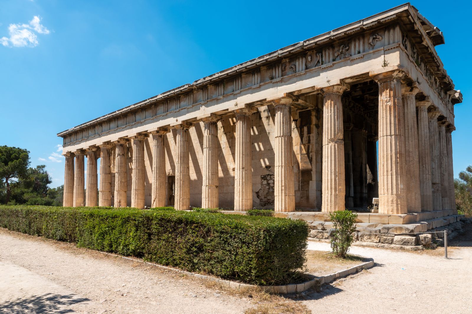 The Temple of Hephaestus in the Ancient Agora of Athens surrounded by cypress and olive trees on a sunny day