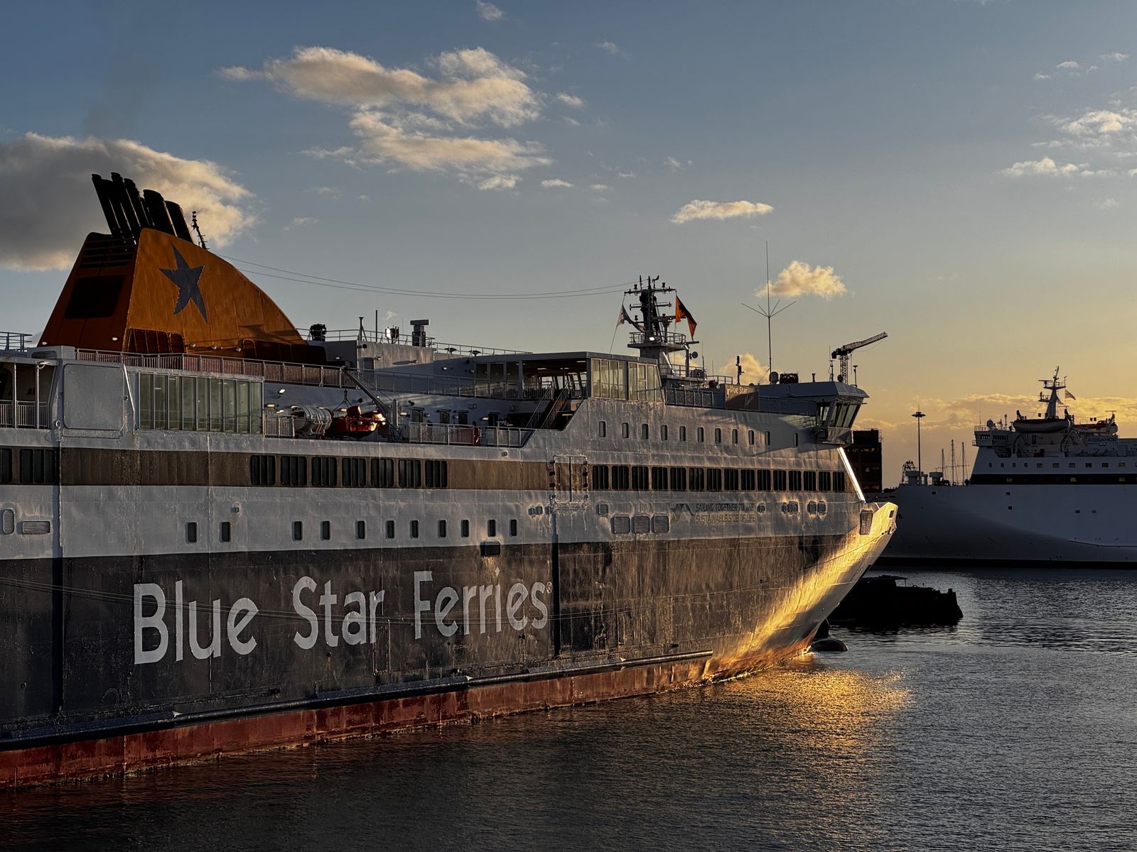 Blue Star ferry docked at Athens port during sunset, ready for departure to the Greek islands
