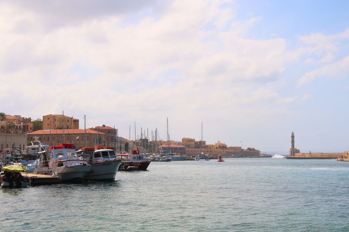 Fishing boats and small vessels docked in Chania's Venetian Harbour with colourful historic buildings in the background