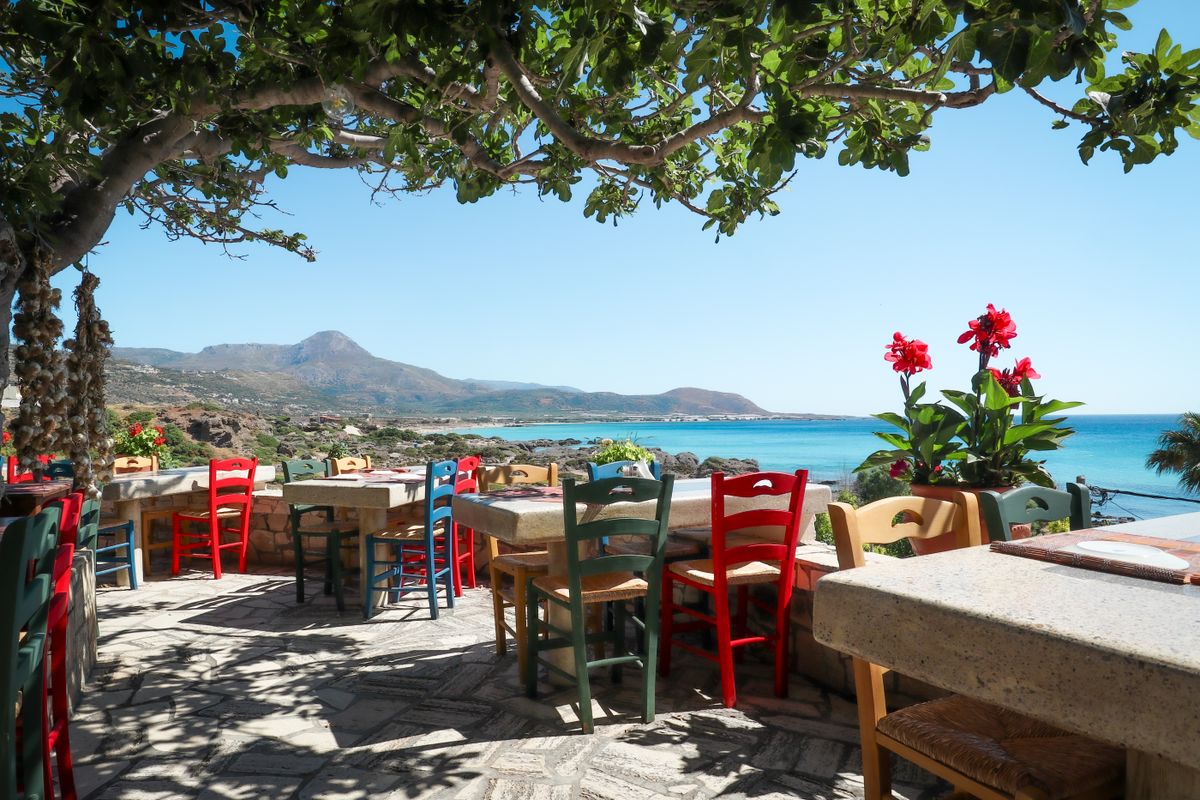A seaside taverna with colourful chairs and tables overlooking the ocean at Phalasarna, western Crete