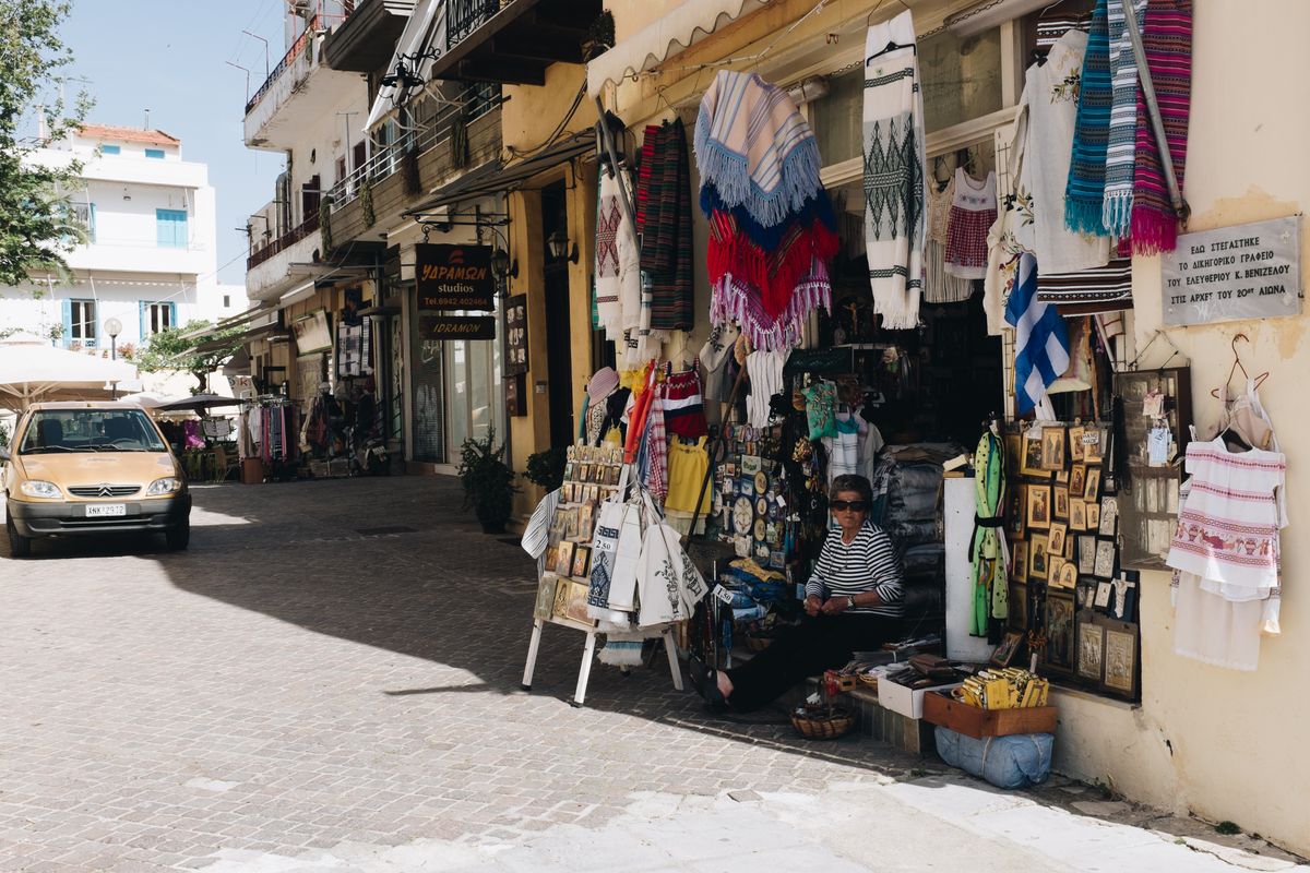 Street market scene in Chania with textiles, traditional crafts, and leather goods on display