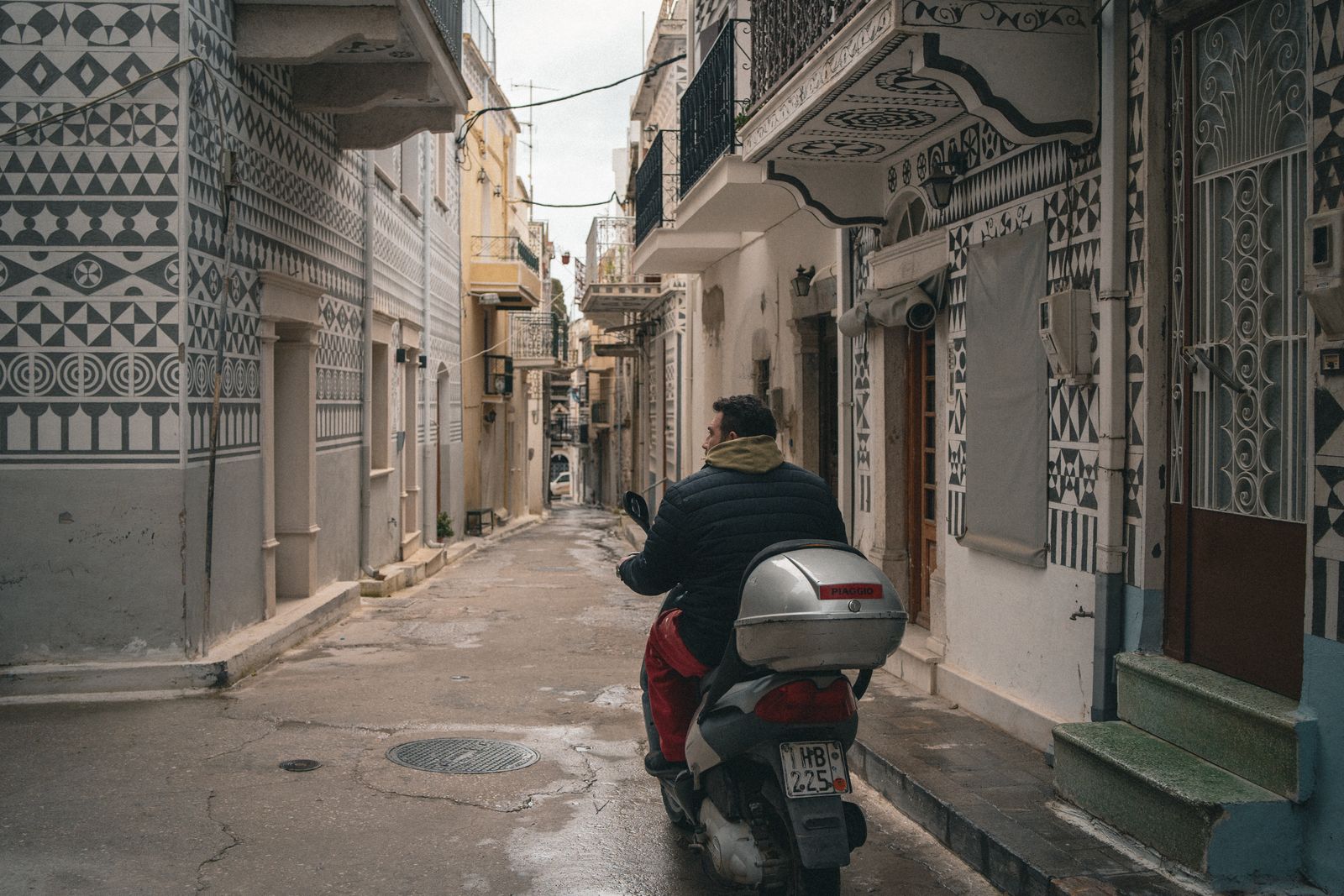 Local rider on a scooter passing through a narrow lane in a mastic village of Chios