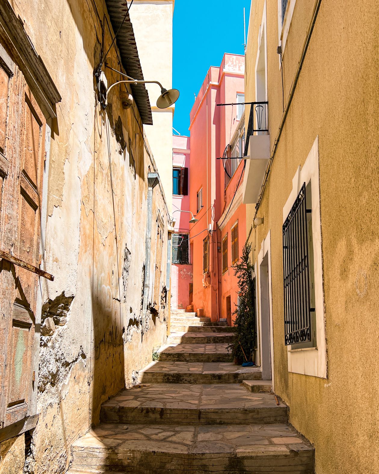 Narrow alleyway with colourful walls and climbing plants in Ermoupoli, Syros