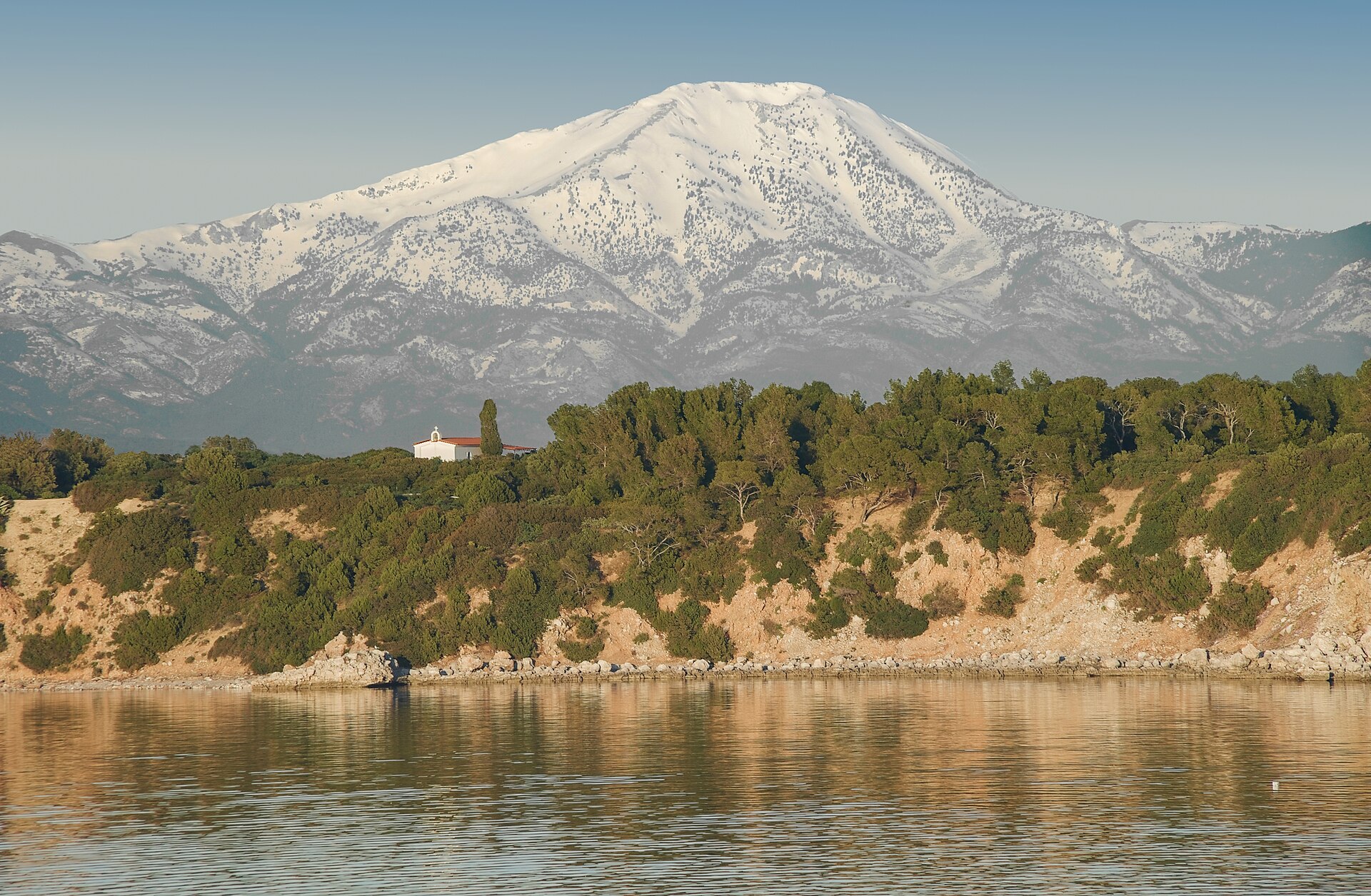 Snow-capped Mount Dirfys seen across the North Euboean Gulf with Ktiponissi island and a church in the foreground
