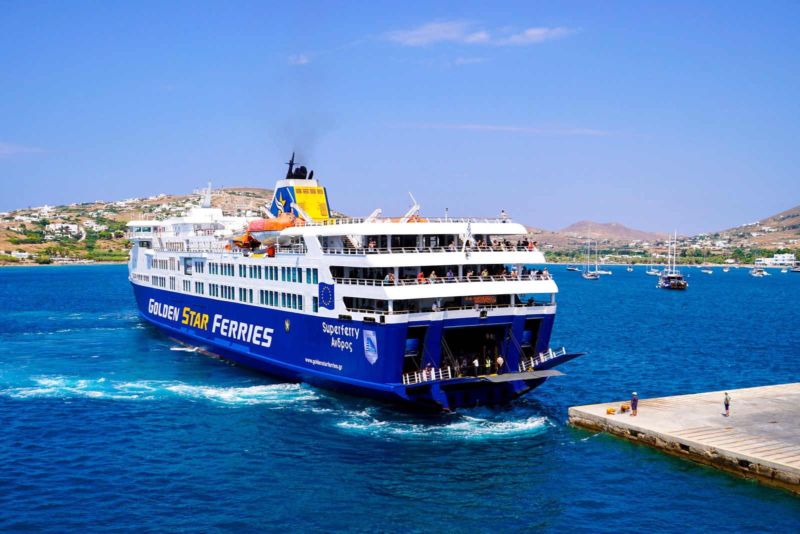 Golden Star ferry approaching a Greek island pier under clear skies in the Cyclades