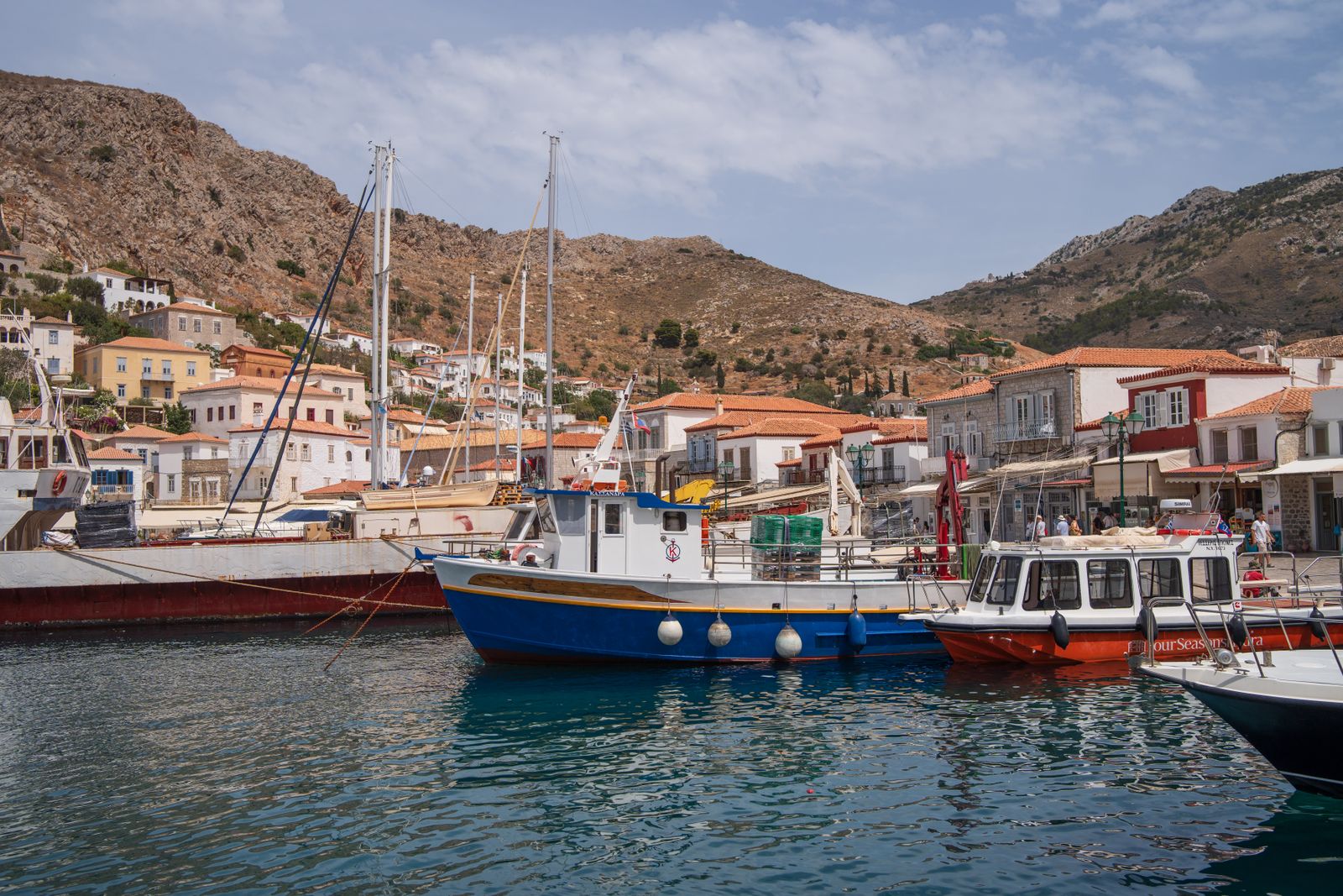 Colourful fishing boats and yachts docked in the marina at Hydra harbour