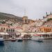 Hydra harbour with the historic clock tower of the Church of the Assumption rising above stone houses and moored boats