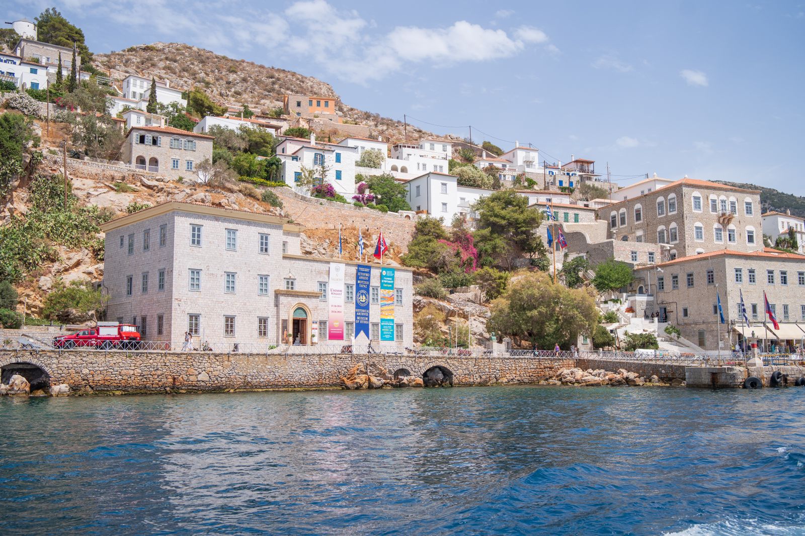 Grey stone houses and traditional architecture rising steeply above the harbour in Hydra Town