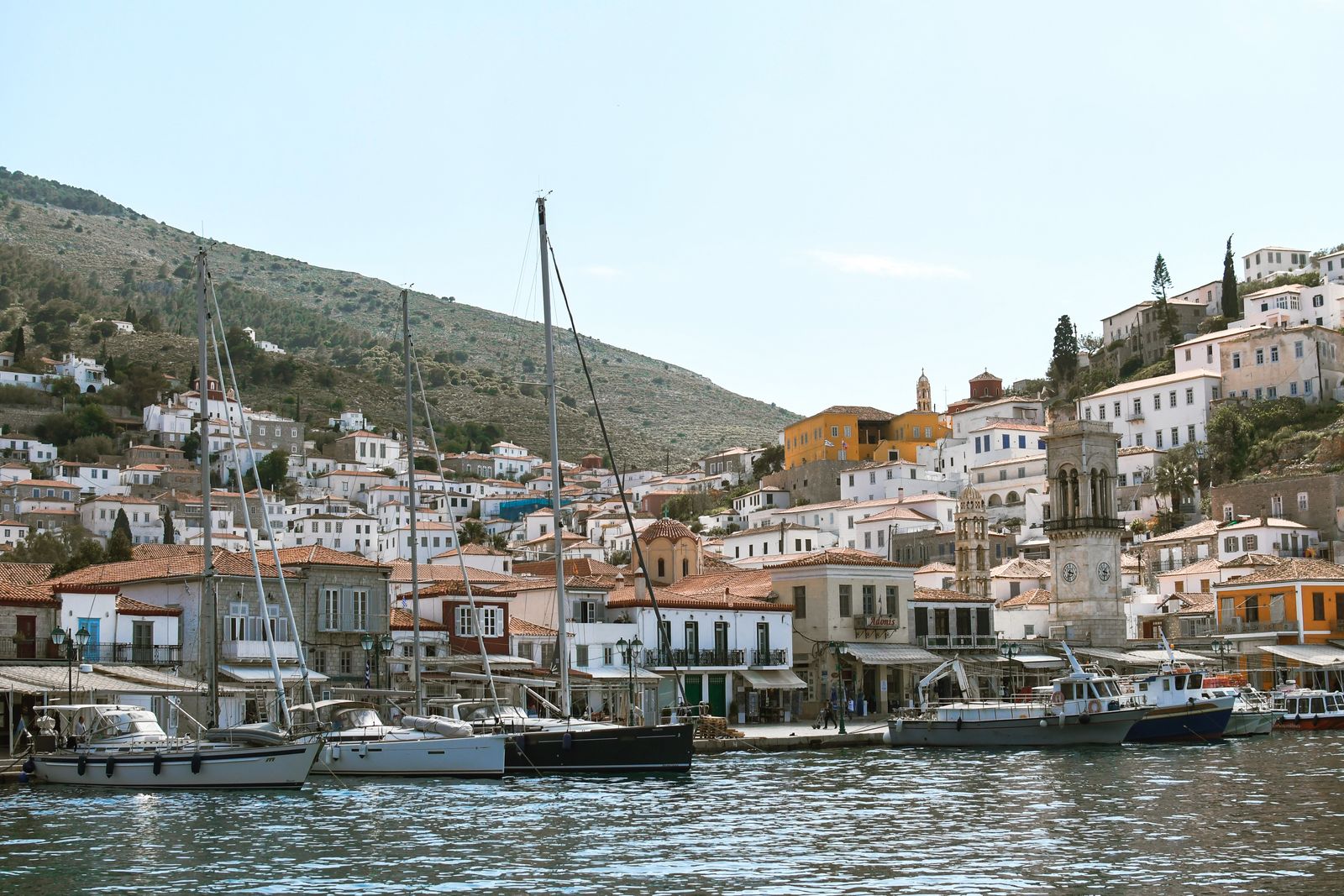 Boats moored along the scenic waterfront of Hydra Town on a clear summer day