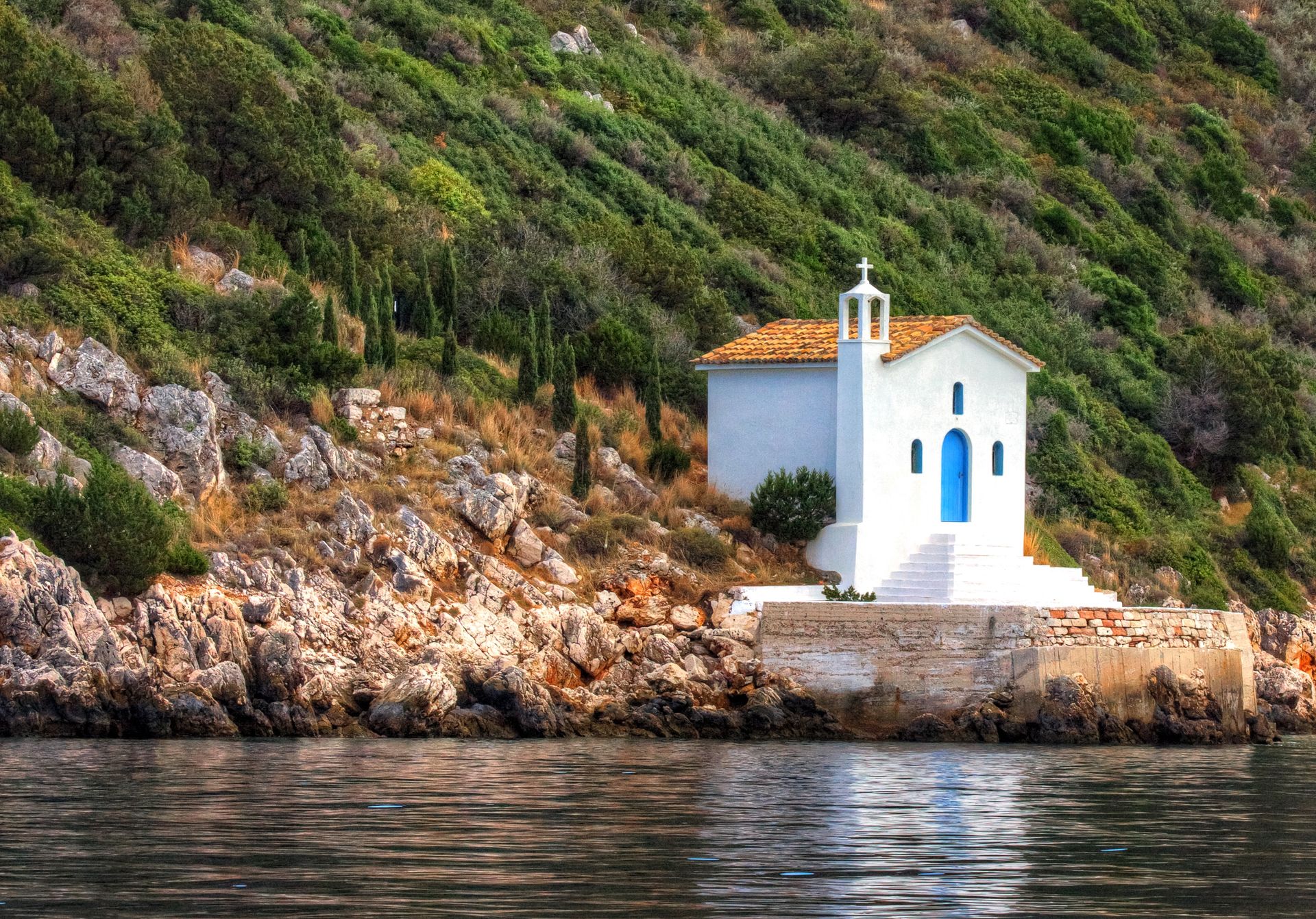 White Orthodox church with blue door by the sea on Ithaca island Greece