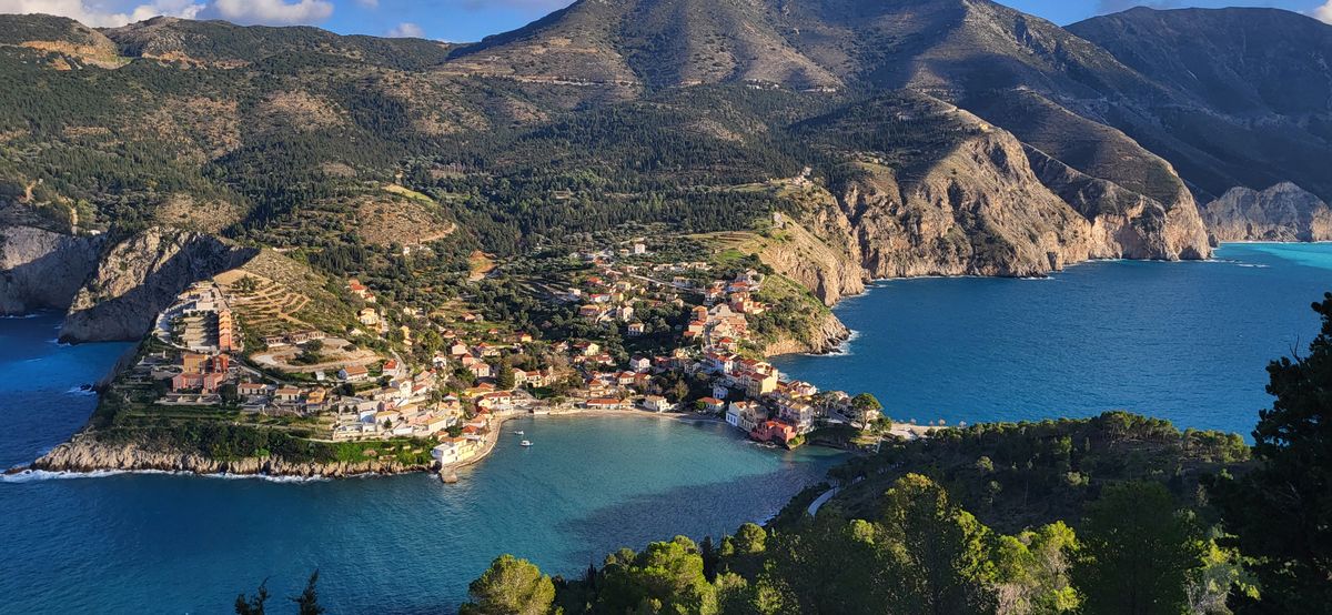 Aerial view of Assos village on its peninsula with the Venetian fortress on the hilltop above the turquoise bay, Kefalonia