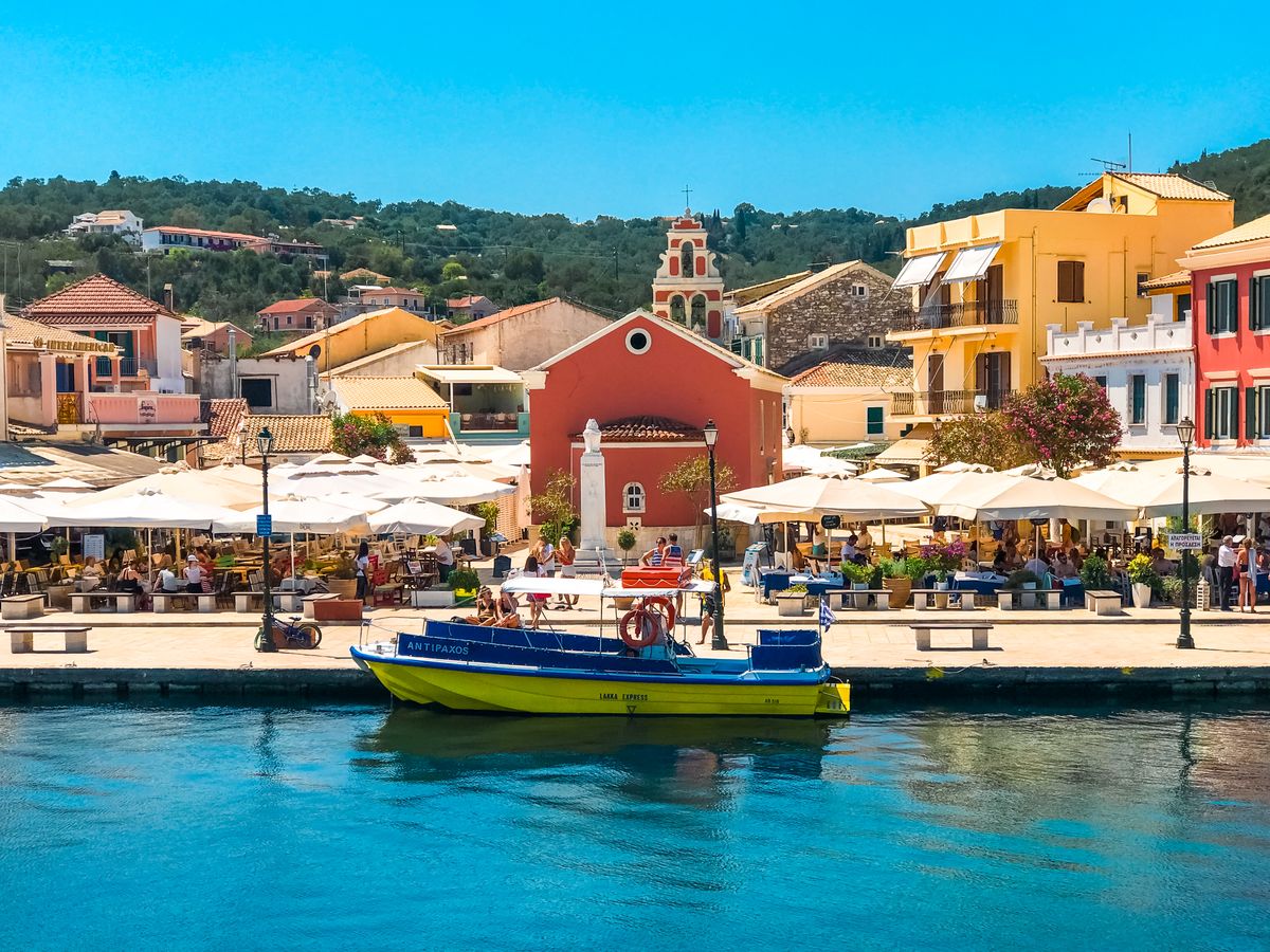 Colourful waterfront buildings and moored boat in Fiskardo harbour, Kefalonia, Greece