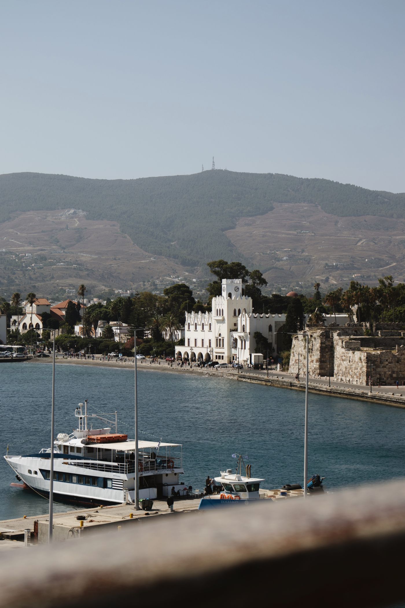 Yacht moored in Kos Town harbour with the town skyline and medieval castle visible behind