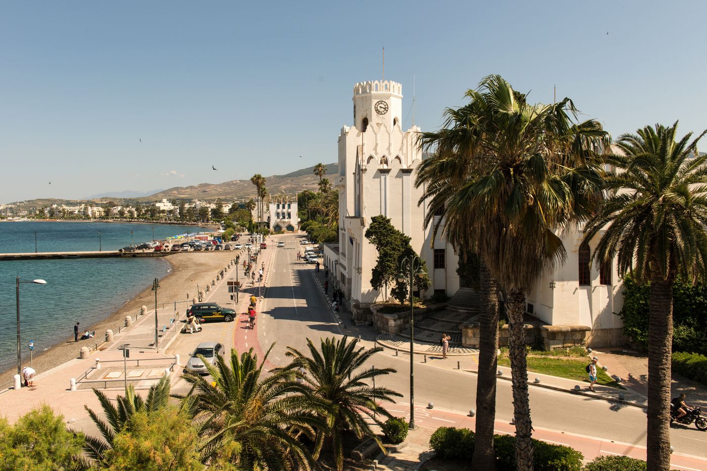 Palm-lined street in Kos Town with historic architecture and cafes in the foreground