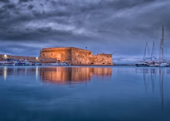 Koules Fortress reflected in calm waters at Heraklion harbour during twilight