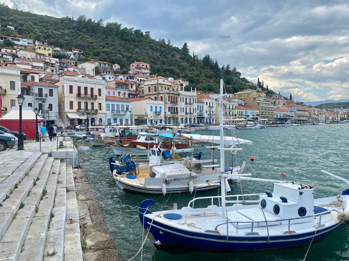 Boats moored in the harbour of Gytheio with colourful hillside buildings behind, Mani, Greece