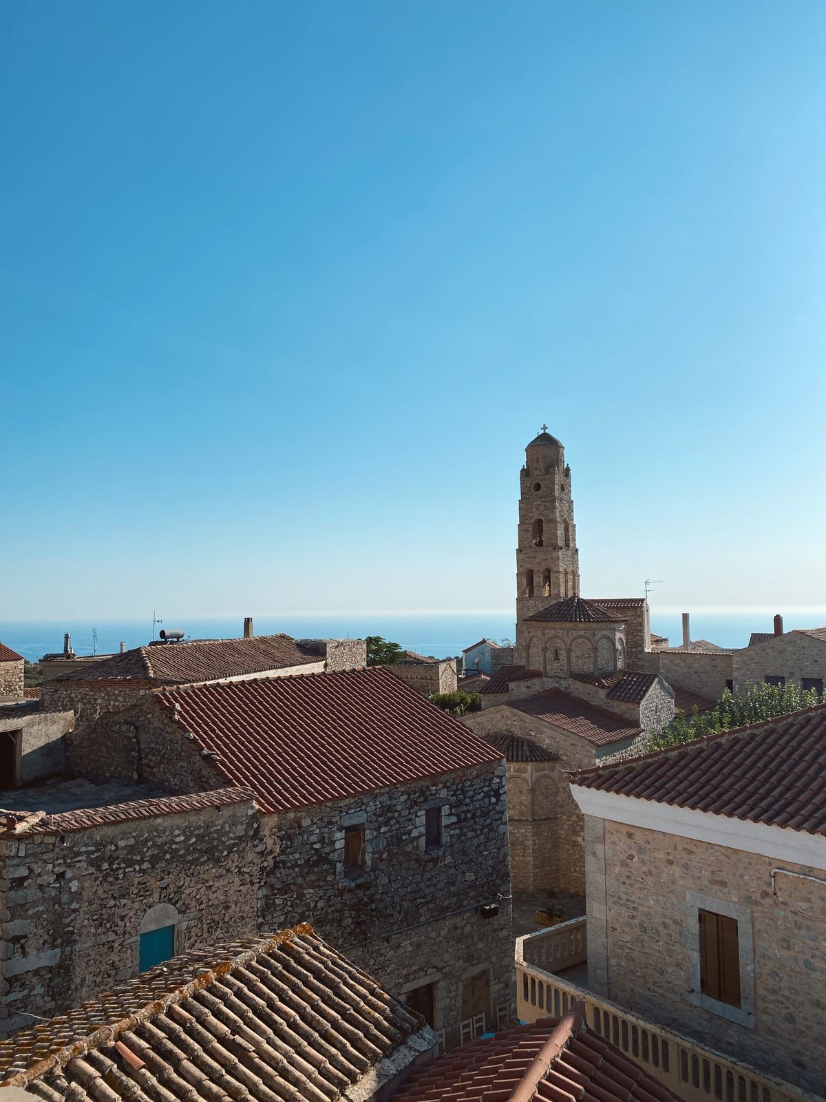 Traditional Mani village with stone tower houses rising above rooftops under a clear blue sky