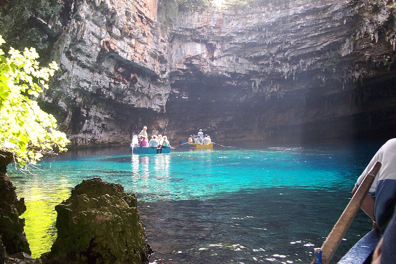 Melissani Cave underground lake in Kefalonia with rowboat and sunlight through opening above