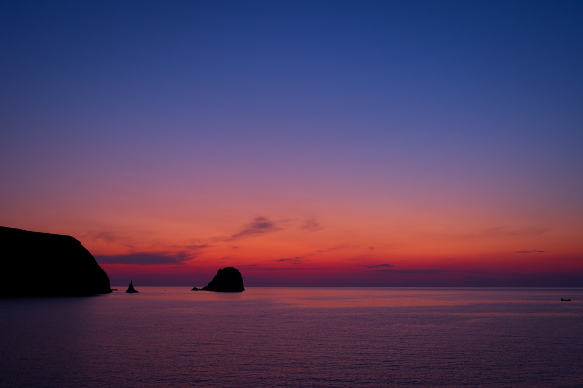 Sunset light over Pollonia village and the calm waters of northeast Milos, with Kimolos island visible in the distance