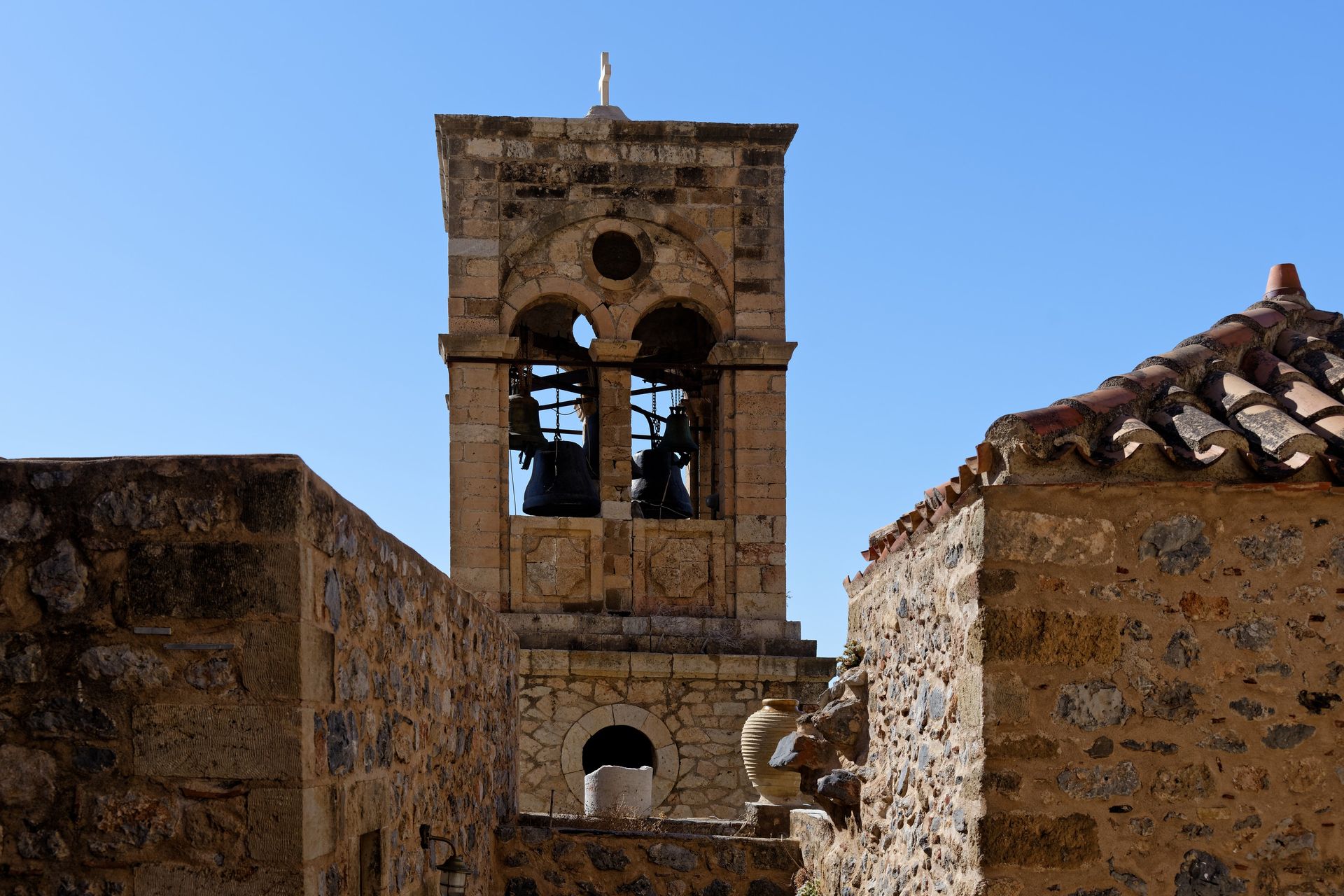Ancient stone bell tower in Monemvasia fortress under clear blue skies