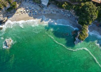 Aerial view of Mylopotamos beach in Pelion, showing turquoise water, white pebbles and forested cliffs