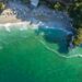 Aerial view of Mylopotamos beach in Pelion, showing turquoise water, white pebbles and forested cliffs