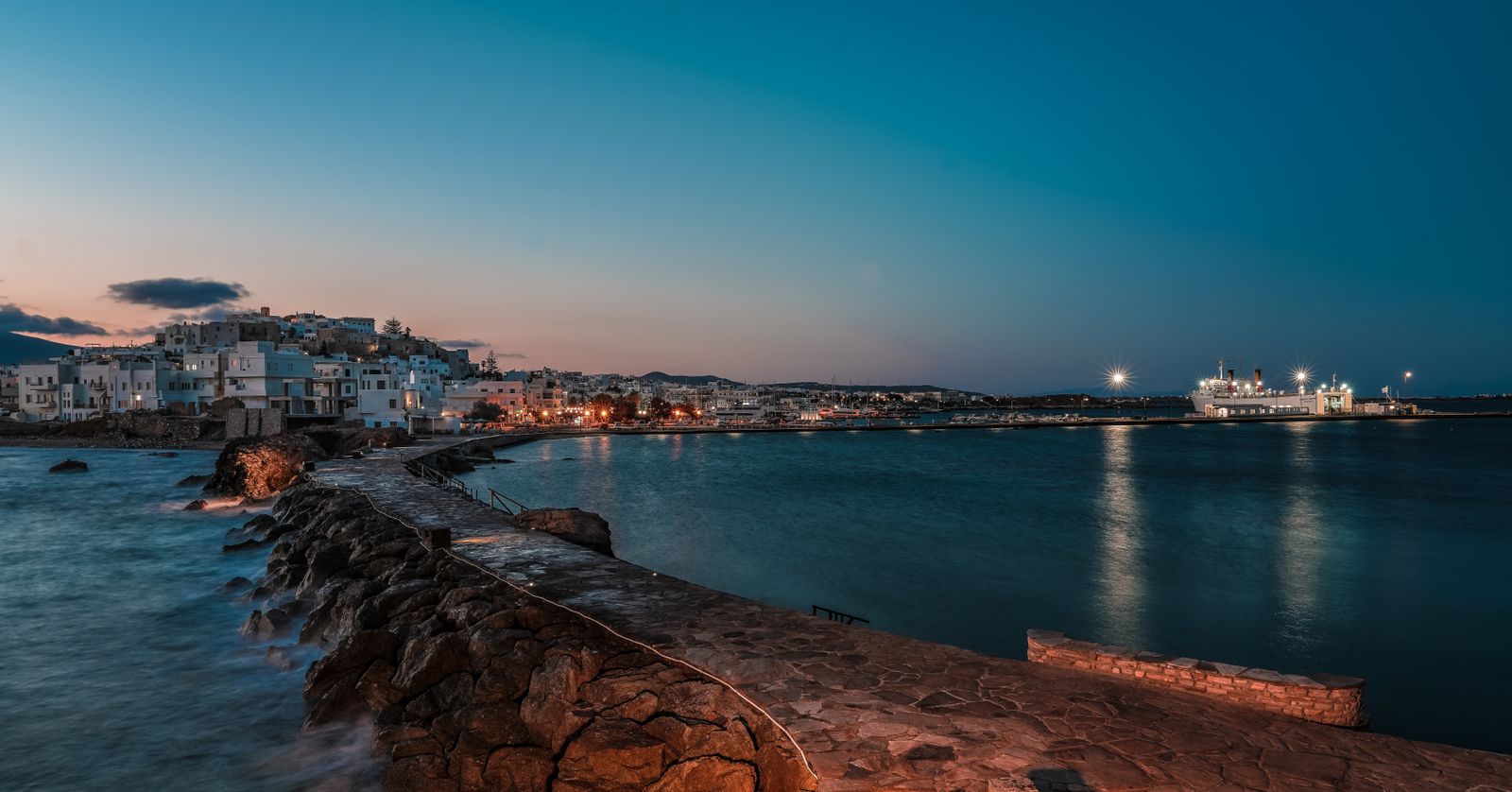 Twilight view of Naxos harbour and Chora with the Portara visible in the distance