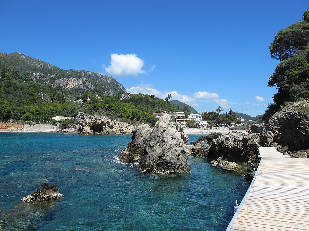 Turquoise bay at Palaiokastritsa Corfu with dramatic cliffs and small fishing boats