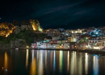 Parga harbour illuminated at night with colourful reflections on calm water