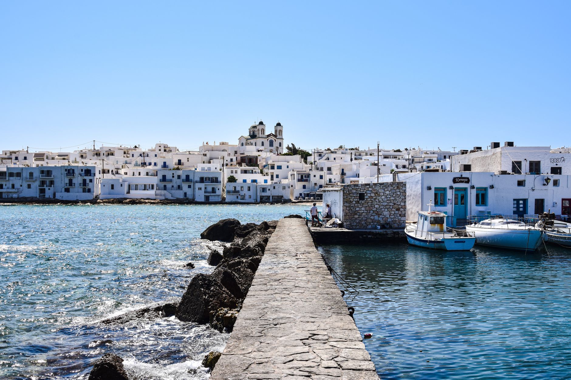 Boats and white buildings along the harbour waterfront of Paros
