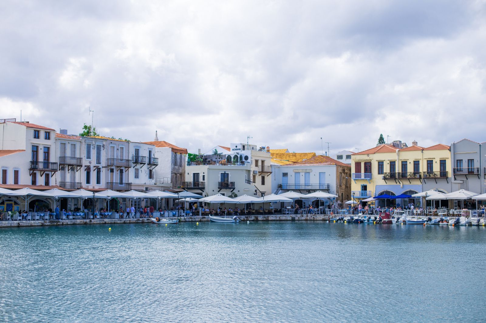 Colourful waterfront buildings and fishing boats along the Venetian harbour in Rethymno, Crete
