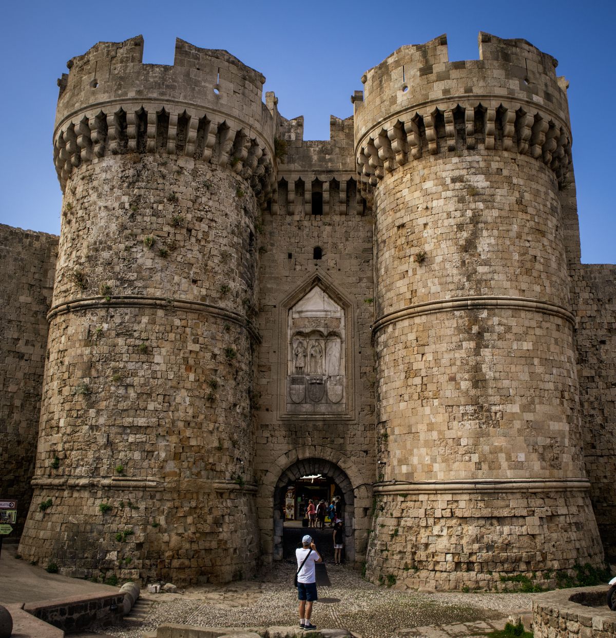 Tourists walking through the fortified gates of the Palace of the Grand Master in Rhodes Old Town