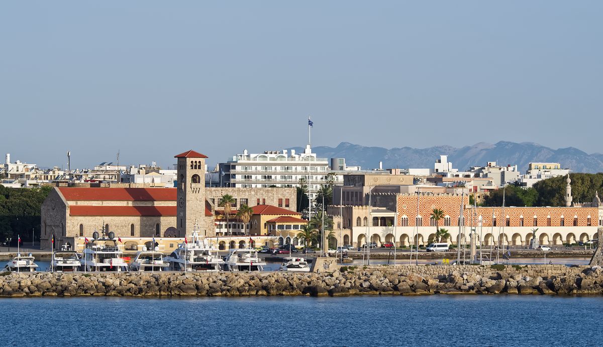 Mandraki Harbour in Rhodes Town with yachts moored and medieval architecture along the waterfront