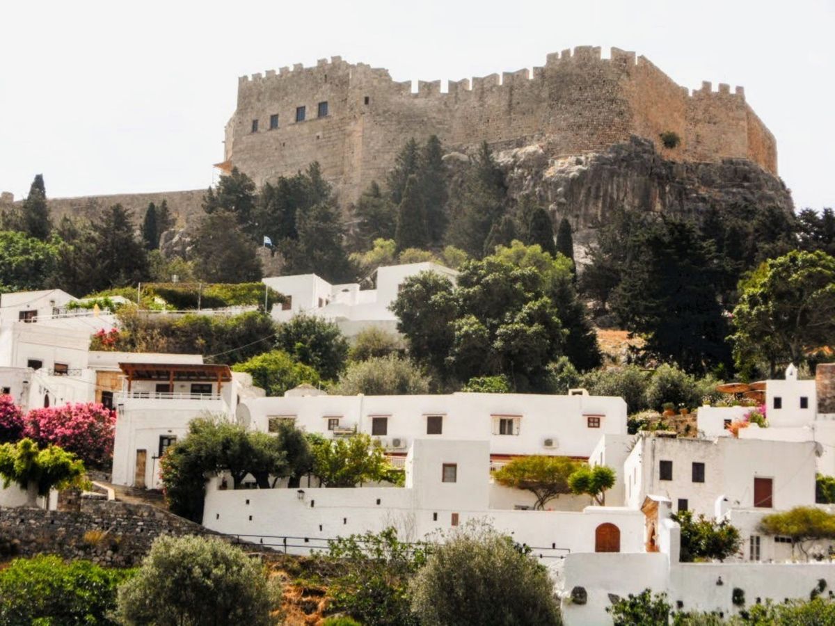 The Acropolis of Lindos rising above traditional whitewashed houses and green vegetation on Rhodes