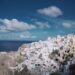 Panoramic view of whitewashed buildings and blue domes along the caldera rim in Oia, Santorini