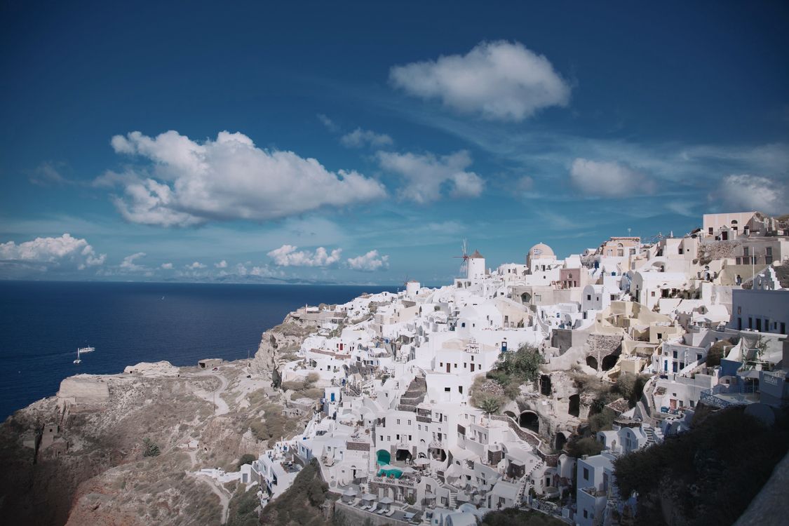 Panoramic view of whitewashed buildings and blue domes along the caldera rim in Oia, Santorini