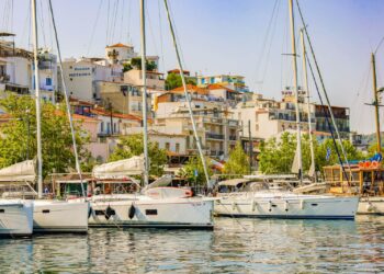 Yachts and sailboats moored in Skiathos harbour with the town rising behind