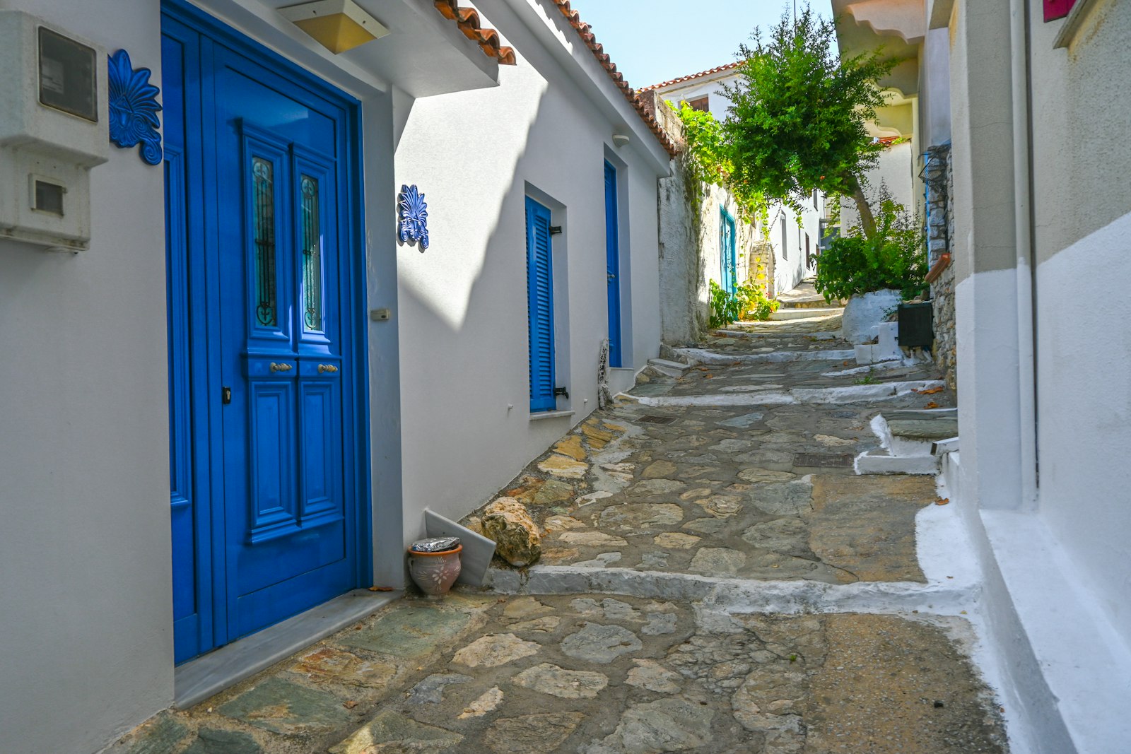 Cobblestone street with blue doors and whitewashed walls in Skiathos old town