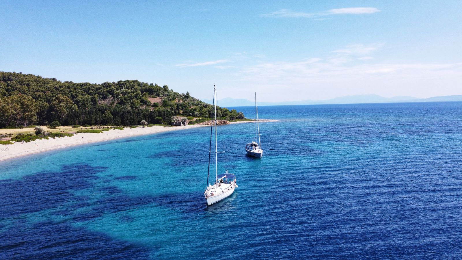Sailboats anchored near the beaches of Tsougrias Island off the coast of Skiathos