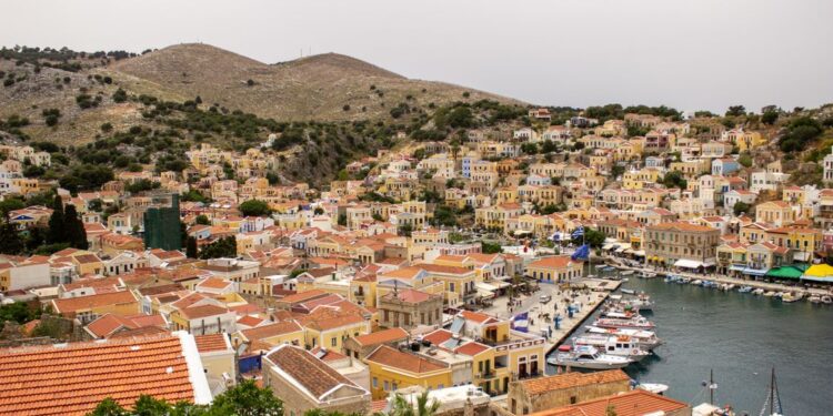 Aerial view of Symi island harbour with colourful neoclassical houses rising up the hillside, Dodecanese, Greece