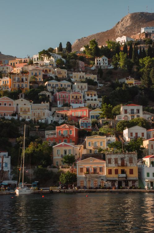 Panoramic view of Symi's colourful hillside houses above the tranquil harbour, Dodecanese, Greece