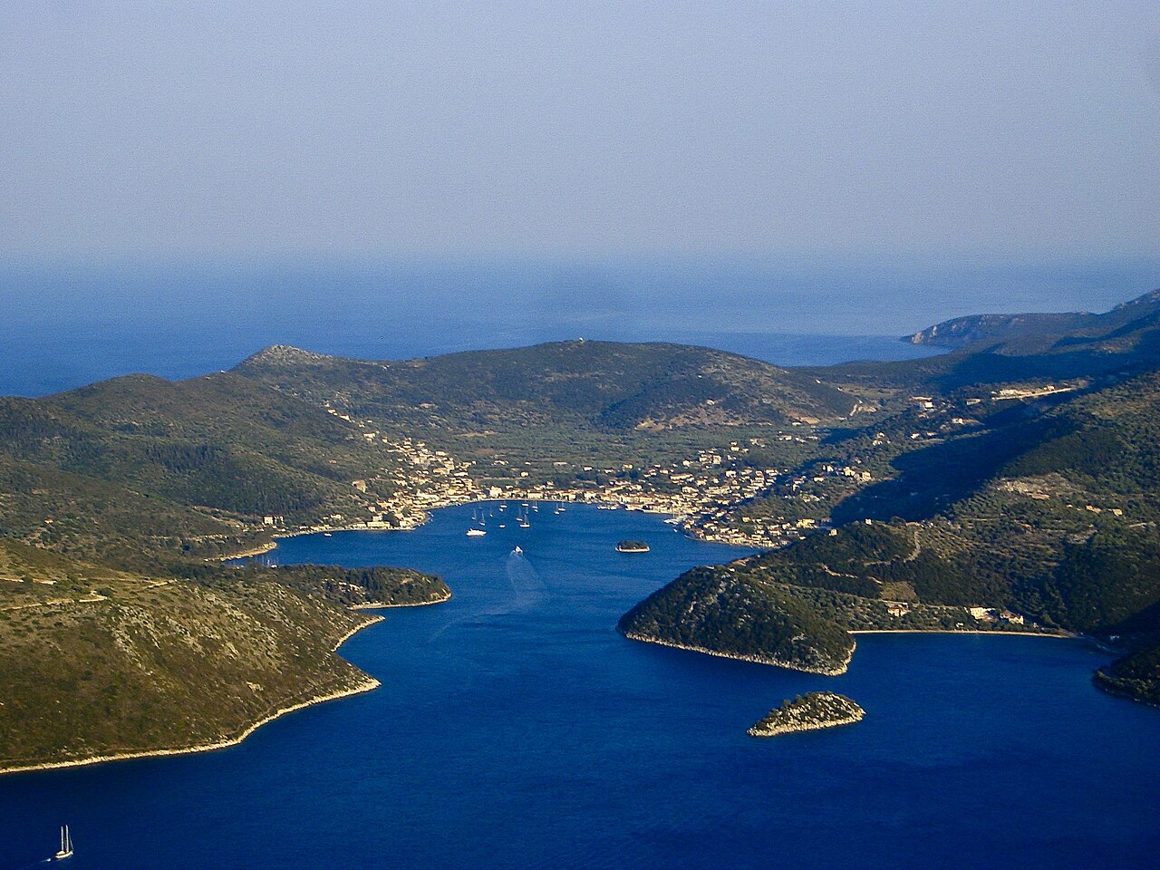 Vathy harbor village in Ithaka Greece with olive-tree covered hills in background